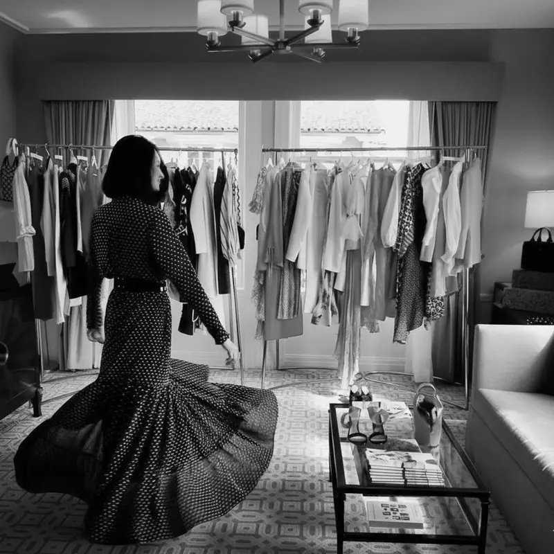 Hotel suite personal styling session — client in a polka-dot dress among curated rails