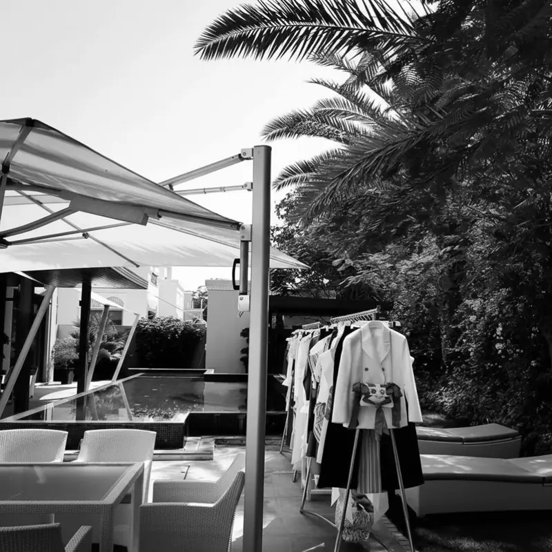 Private styling session in Kuwait — curated clothing rail beside a garden pool