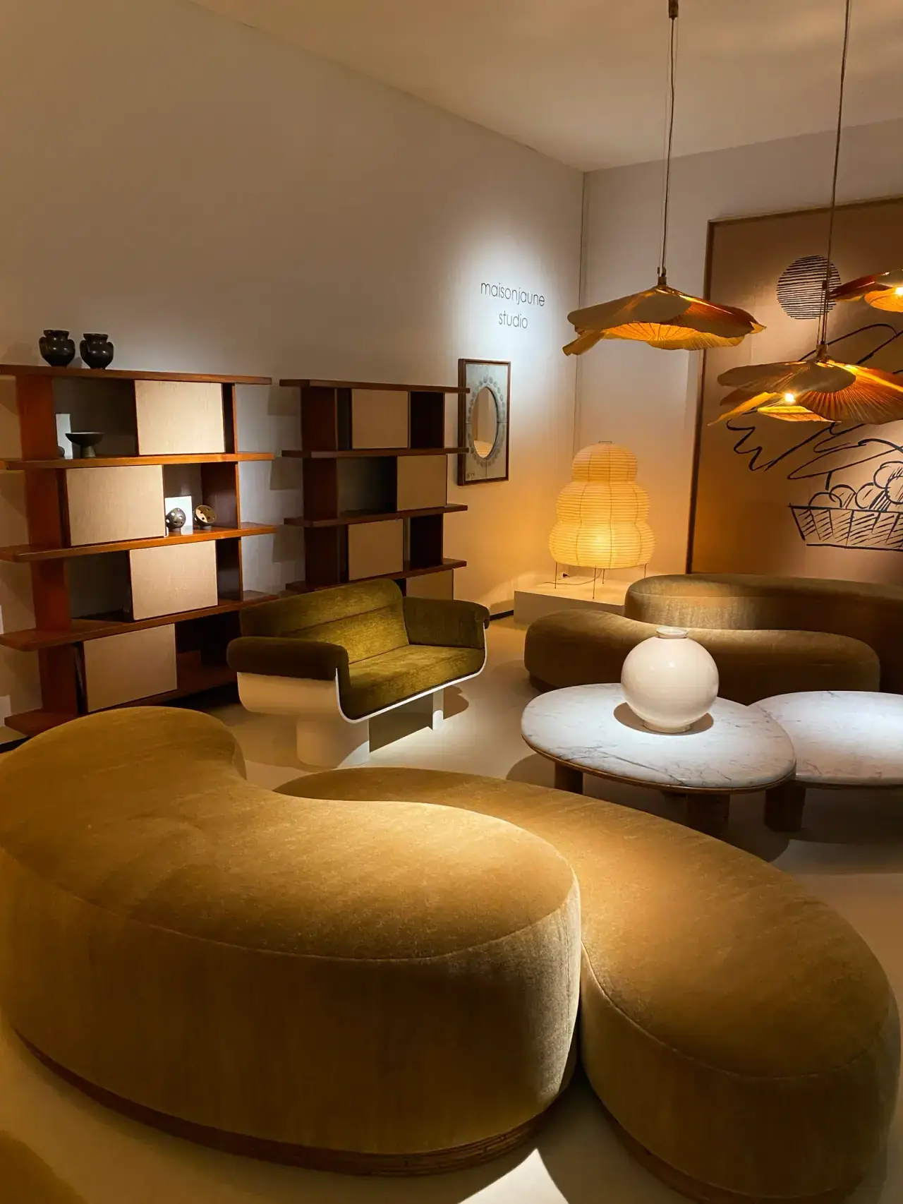 Curated living room with curved velvet sofas, marble tables and paper lanterns